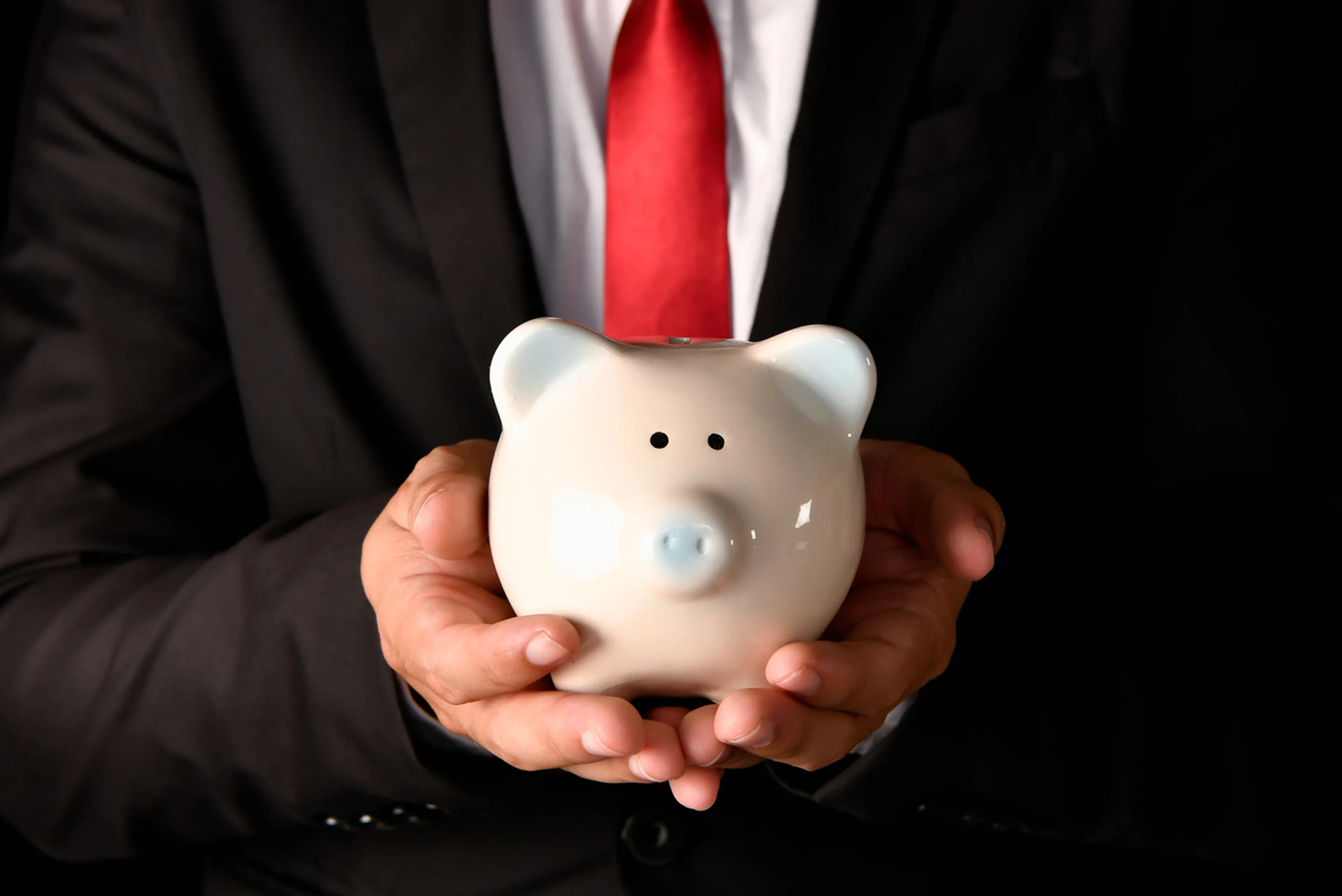 Businessman holding a piggy bank symbolizing savings.