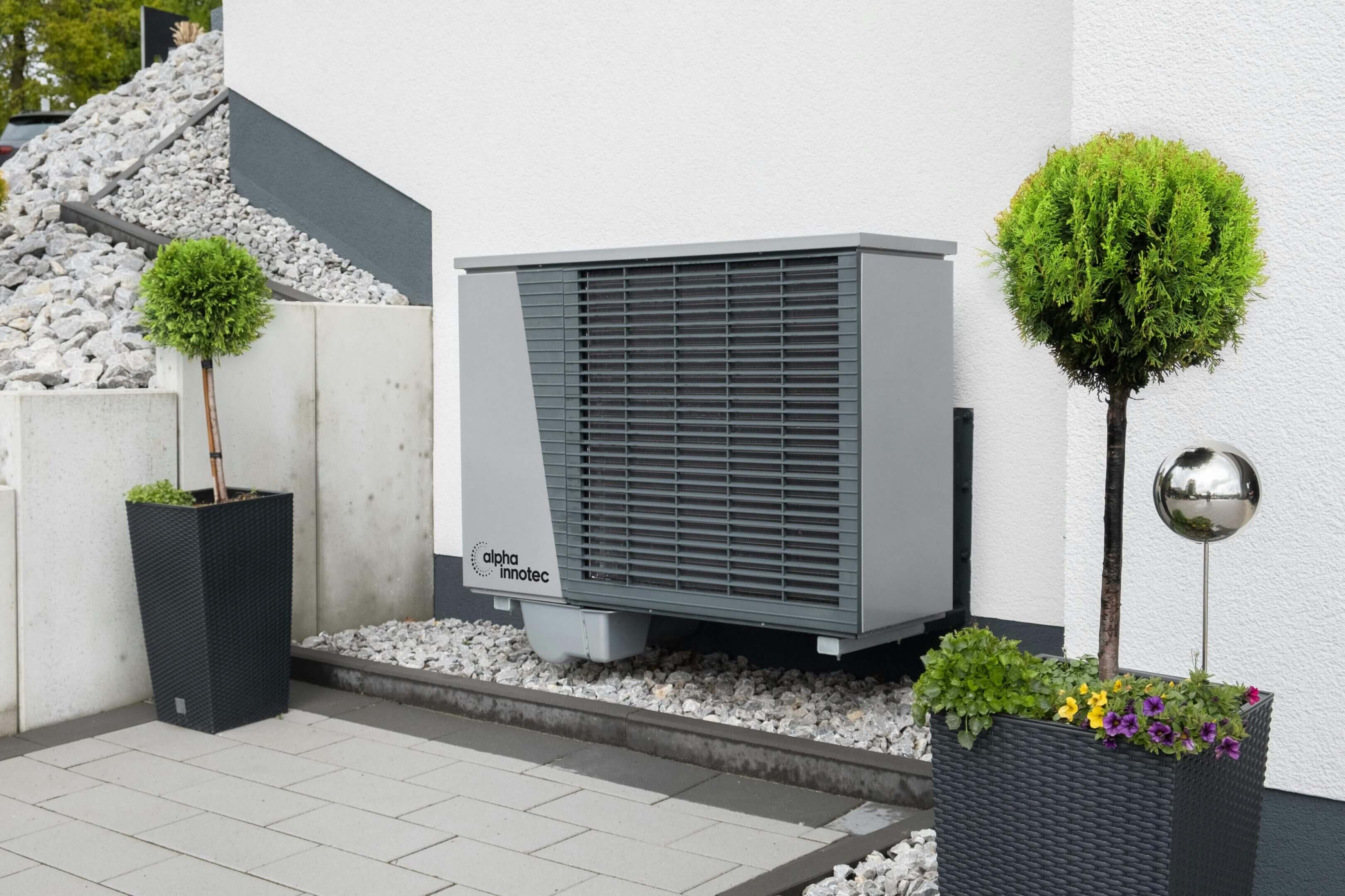 Modern heat pump installed on a bed of stones outside a home.