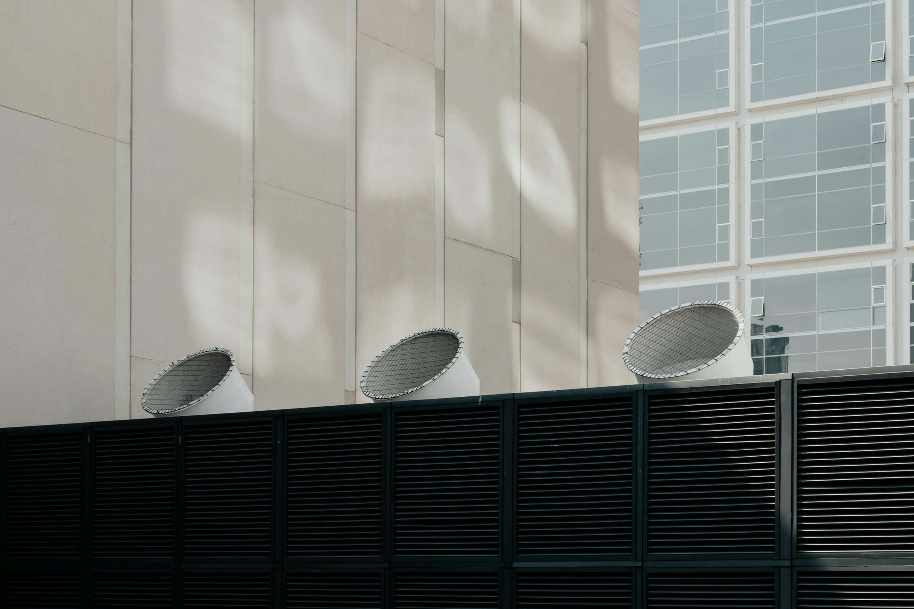 Satellite dishes mounted on a building rooftop under soft daylight.