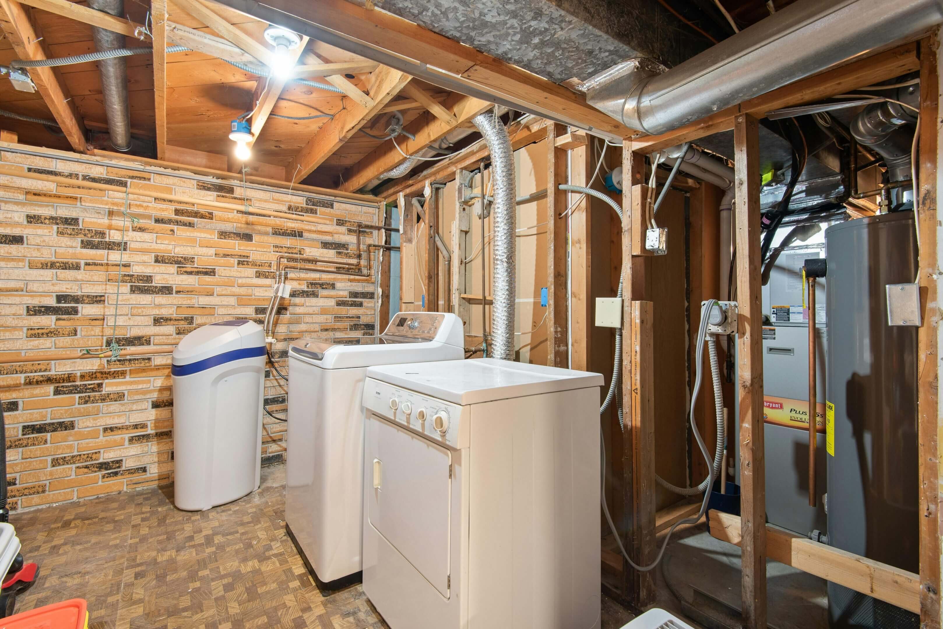 Laundry room with washer, dryer, and exposed brick walls.