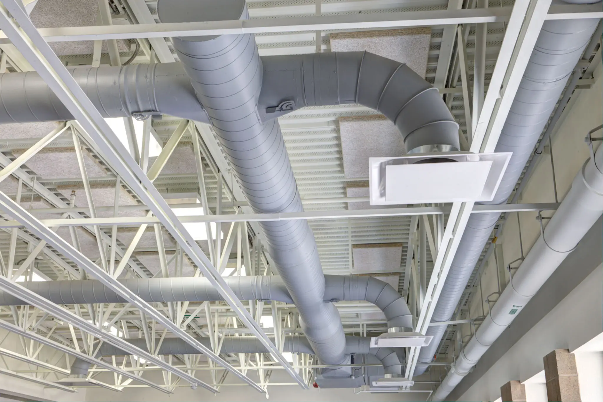 Industrial ceiling with exposed HVAC ducts and metal framework.