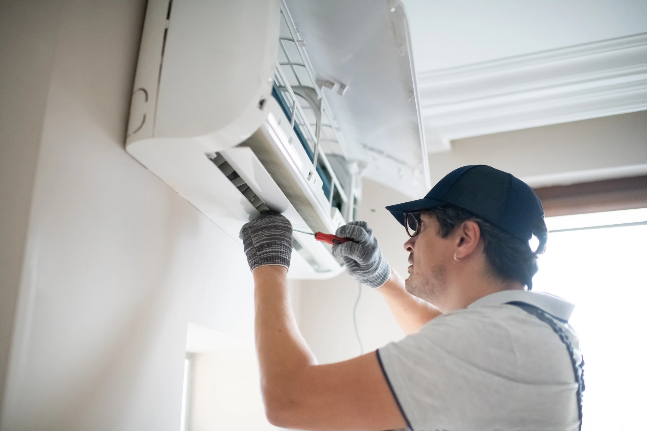 Technician repairing a wall-mounted air conditioner.