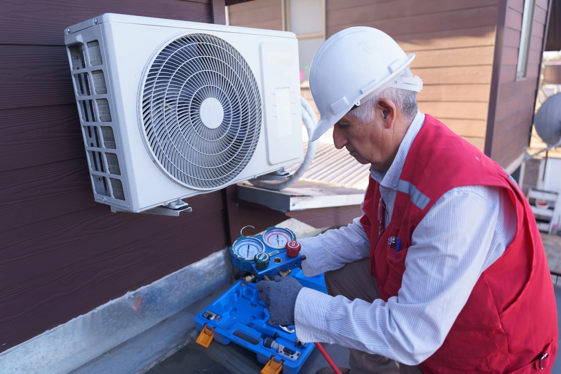Technician servicing outdoor air conditioning unit.