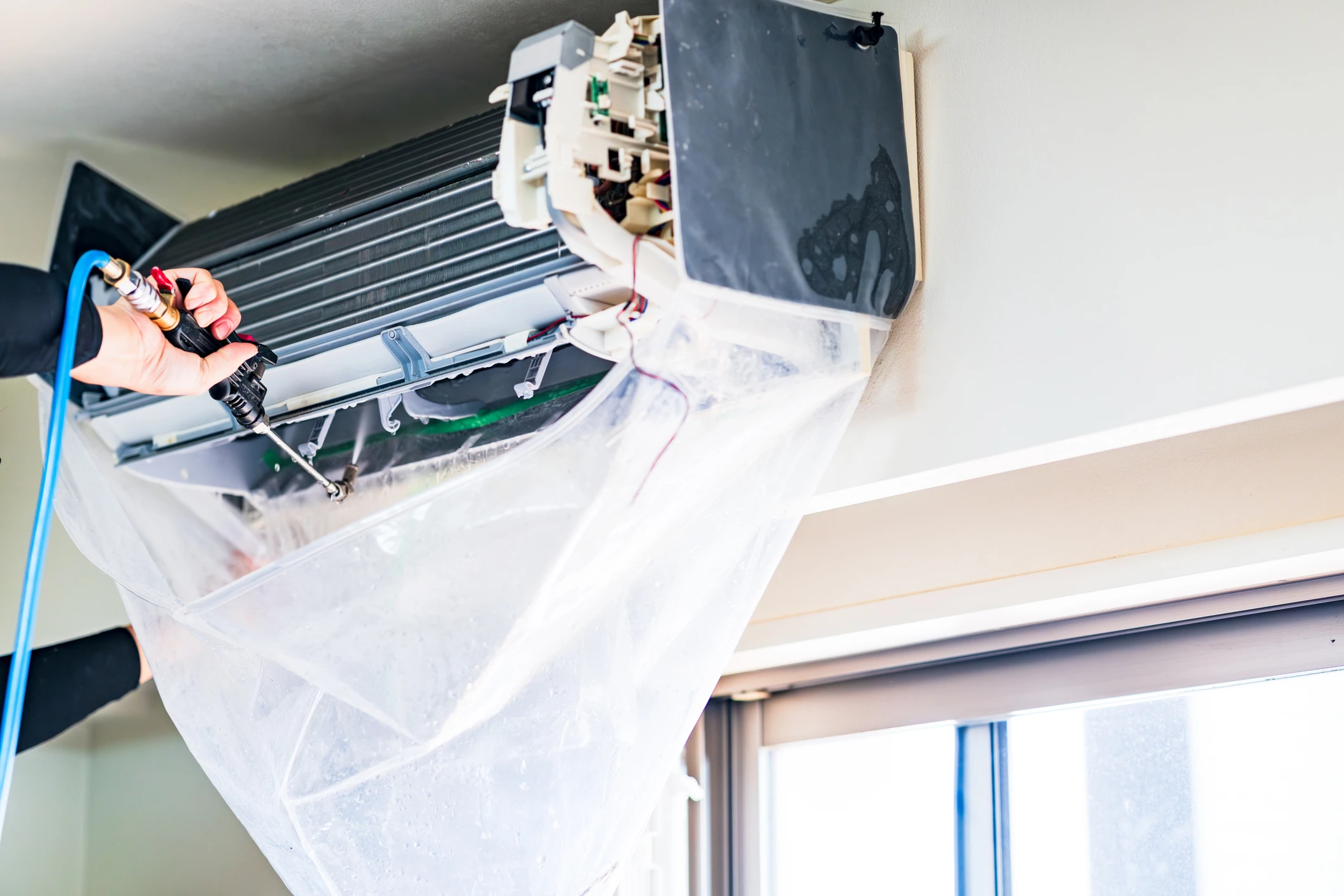 Cleaning a wall-mounted air conditioning unit.