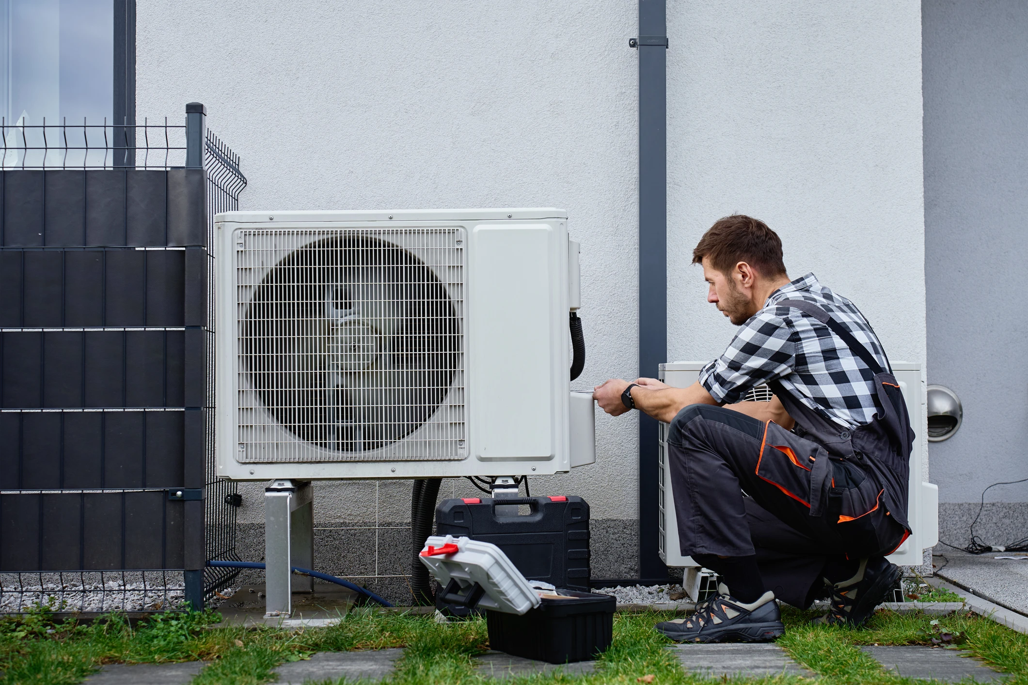 Technician repairing outdoor air conditioning unit.