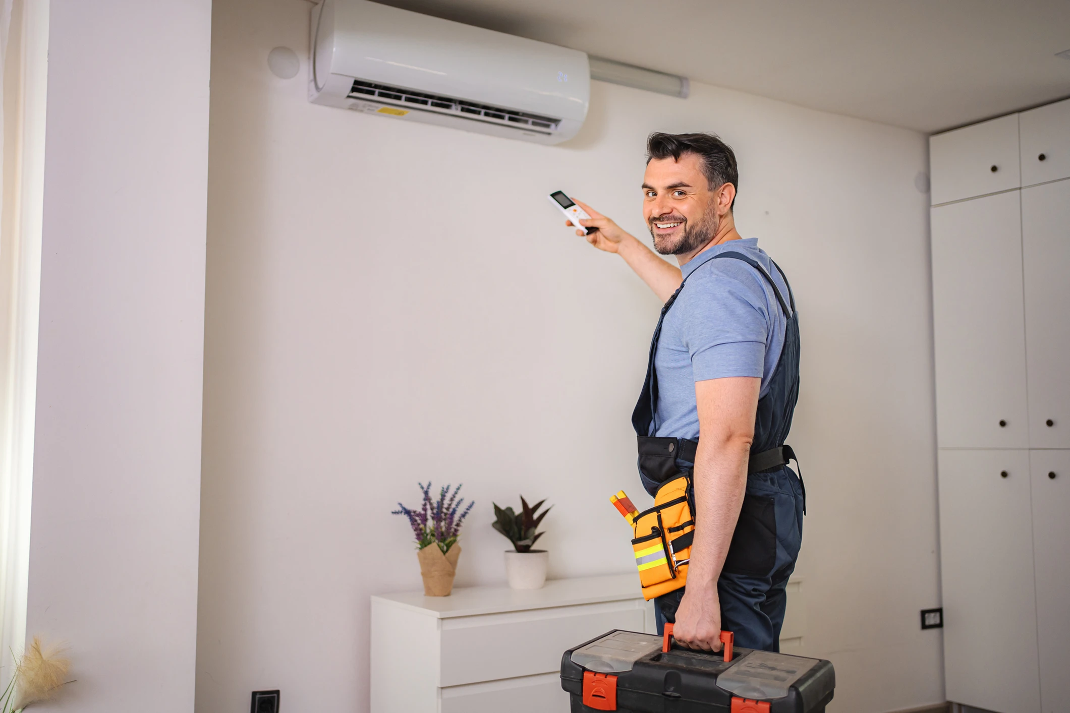 Man adjusting wall-mounted air conditioner unit.