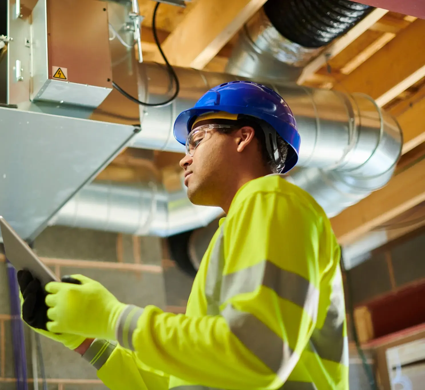 Worker inspecting HVAC system with tablet.