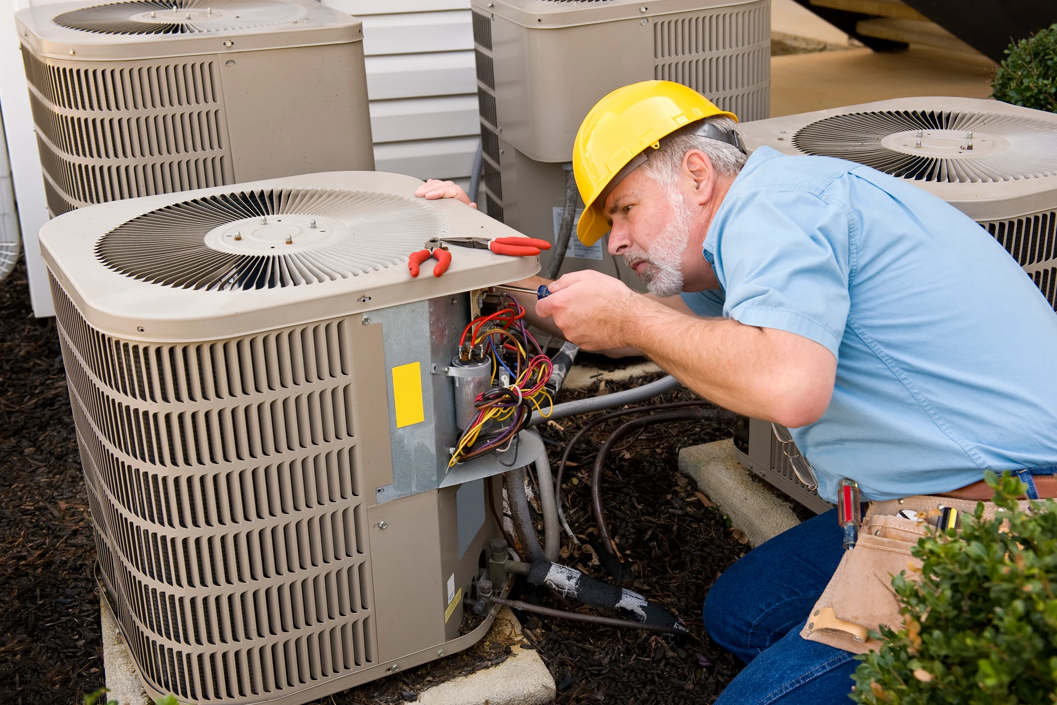 Technician repairing outdoor air conditioning unit.