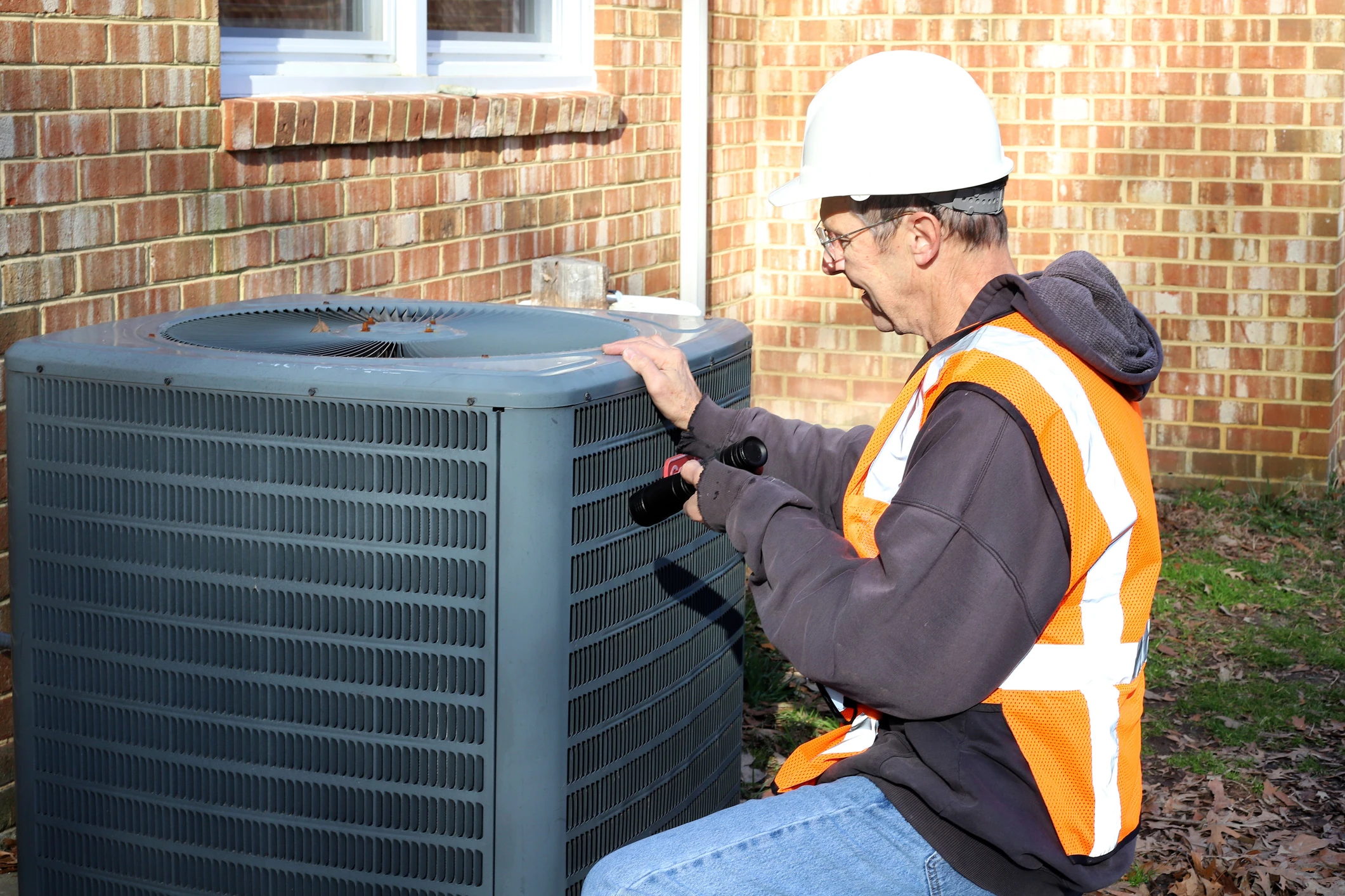 Technician repairing outdoor air conditioning unit.