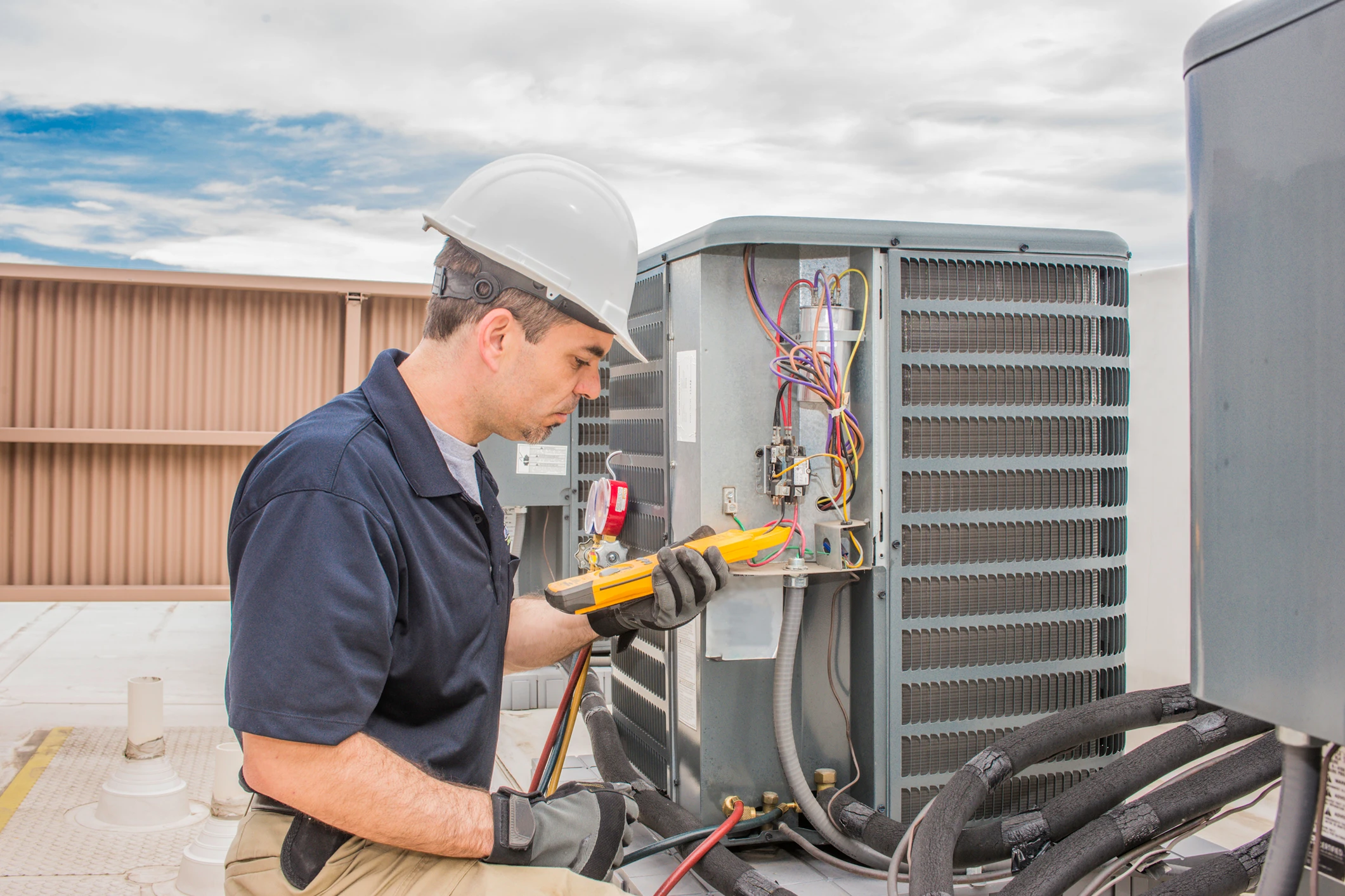 Technician repairing rooftop air conditioning unit.