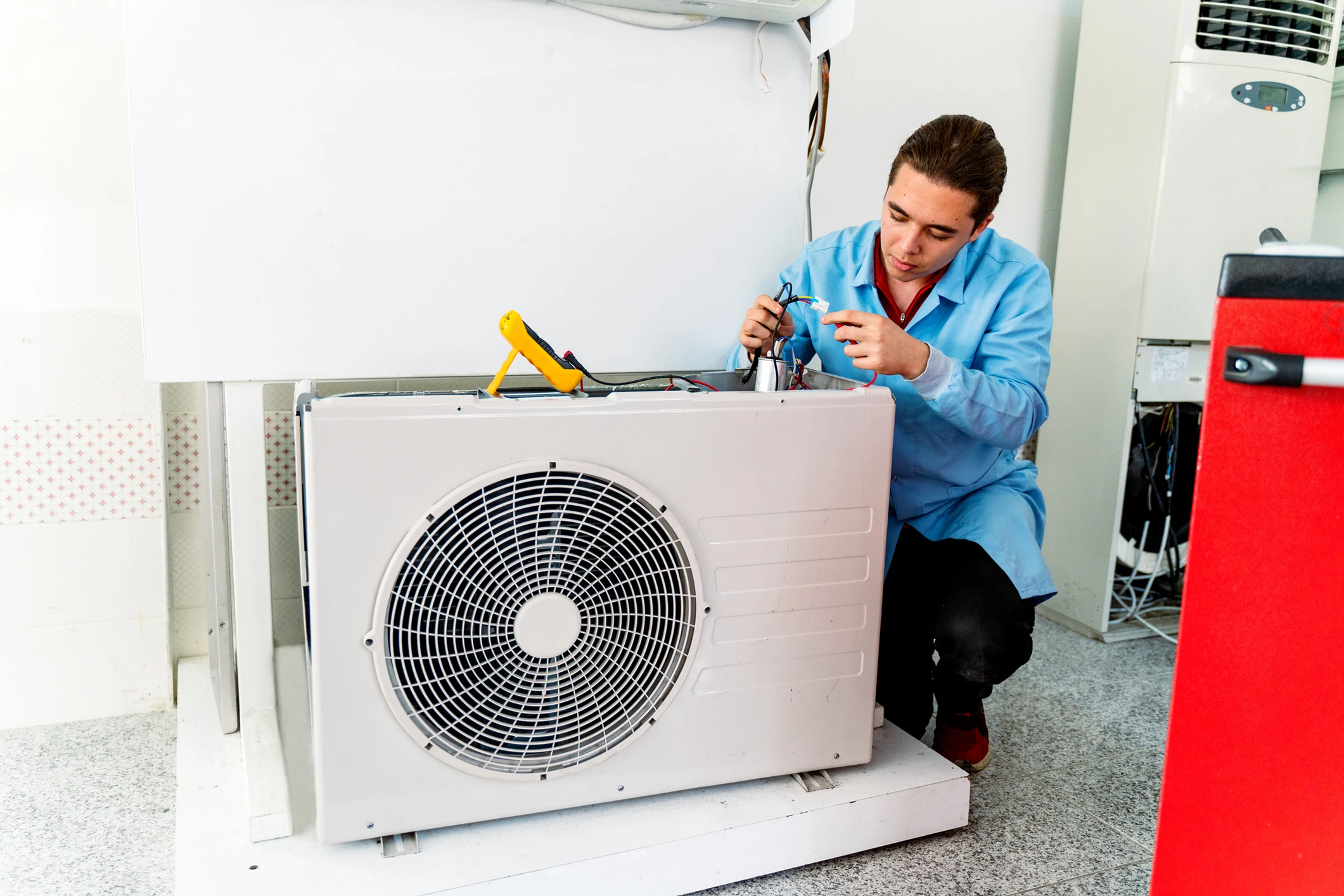 Technician repairing air conditioning unit indoors.