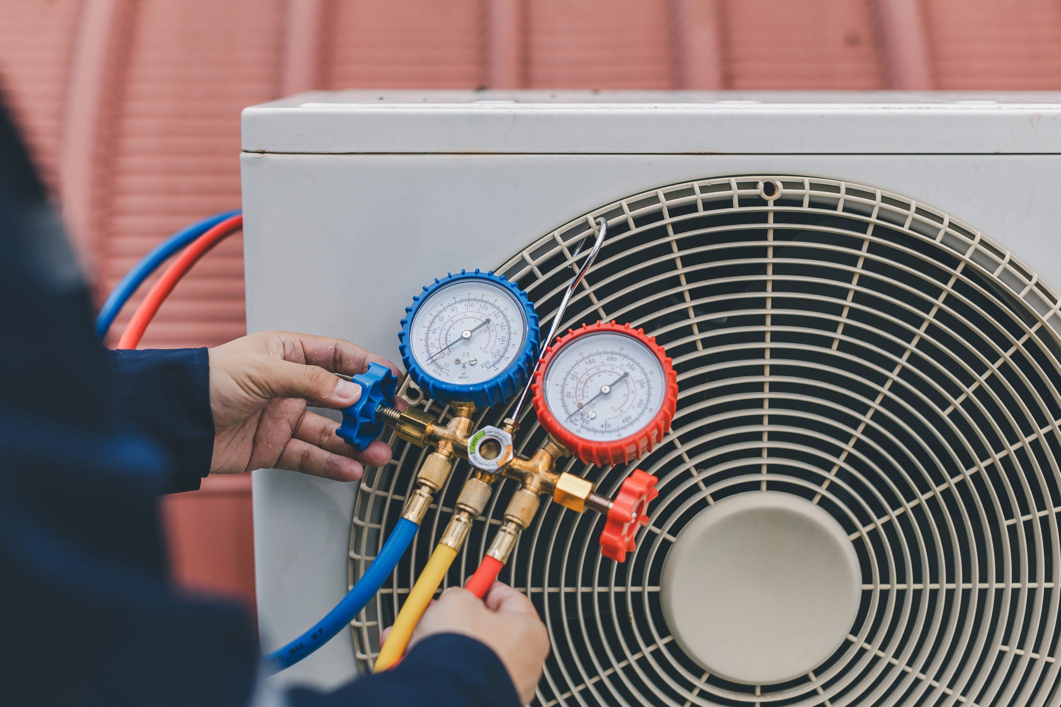 Technician adjusting air conditioning unit gauges.