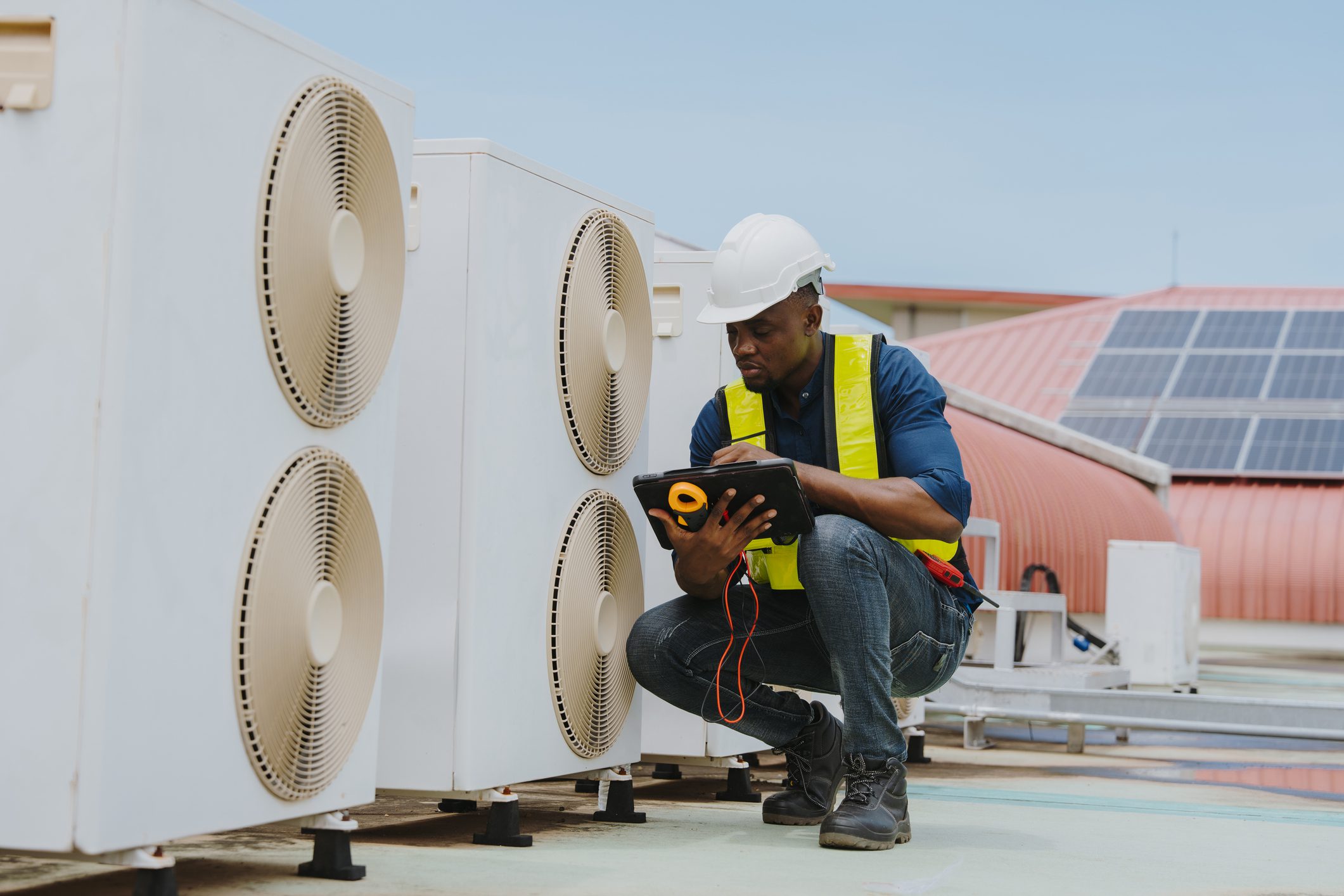Technician inspecting rooftop air conditioning units.