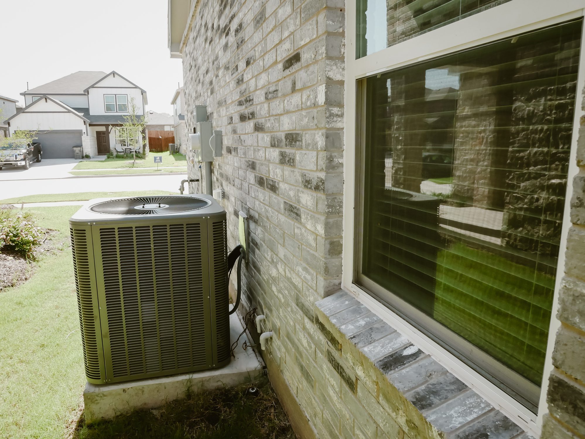 Air conditioner unit outside brick house.